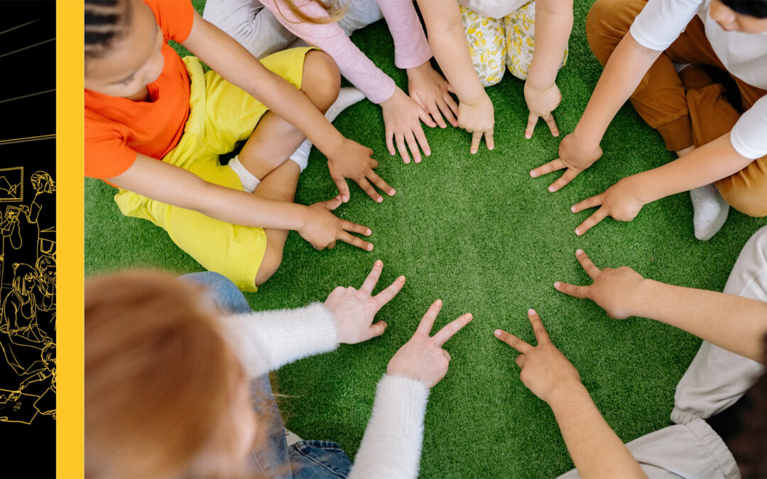 Top-down image of children sitting in a circle with their hands on the floor in front of them
