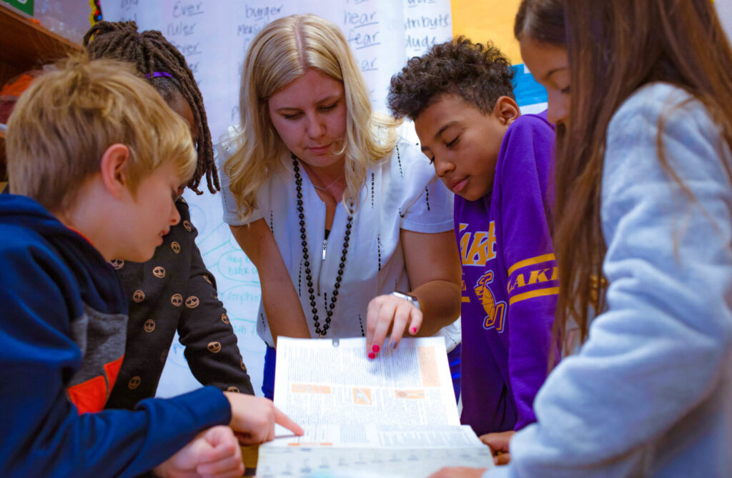 A MPS teacher works with a group of students on an English assignment (2019).