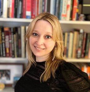 Annie Ferrell headshot standing in front of a bookcase.