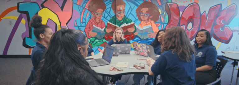 A group of six educators sit around a table at the Detroit Academy of Arts and Sciences.